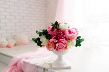 Bir vazoda peonies buket. Pembe peonies. Saydam vazo. Beyaz masa. Beyaz duvar kağıdı. Beyaz dekor. Çiçekler odası.