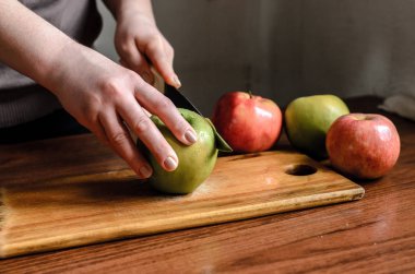 kadın eli bir mutfak bıçağı ile bir ahşap tahta üzerinde büyük kırmızı elma biler