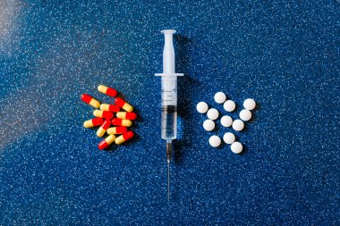 şırınga ve mavi bir arka plan üzerinde ilaç