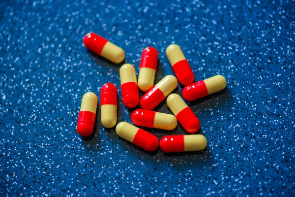 Red and yellow capsule medication on a blue background