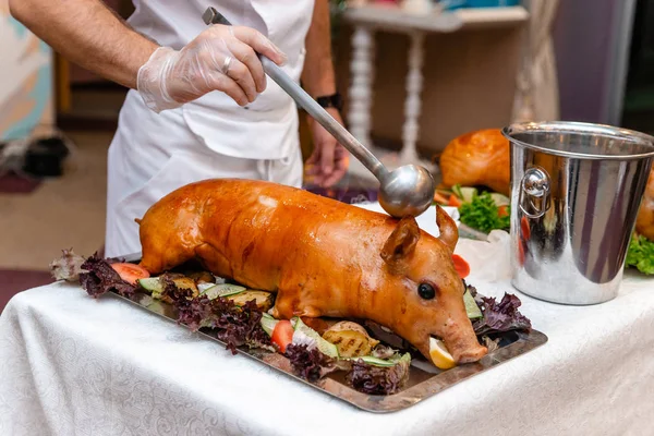 Roasted whole pig decorated with bright vegetables such as bell pepper and cucumbers. Side view