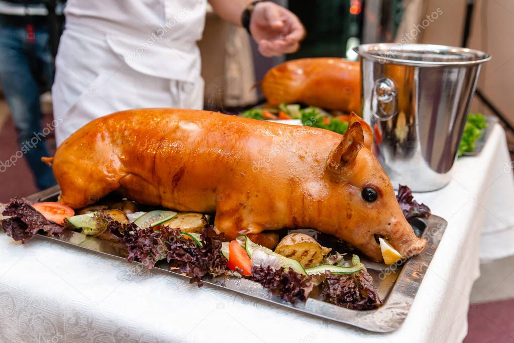 Roast pig. Roasted piglet with vegetables on platter