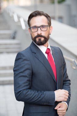 Takım elbiseli ciddi bir işadamının portresi sana gözlüklerle bakıyor.