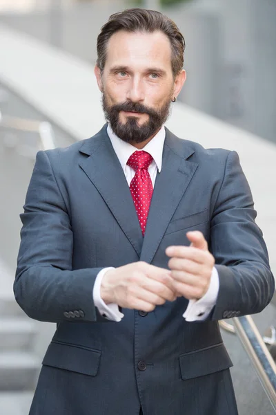 Empresário positivo fixando cuidadosamente suas mangas da camisa — Fotografia de Stock