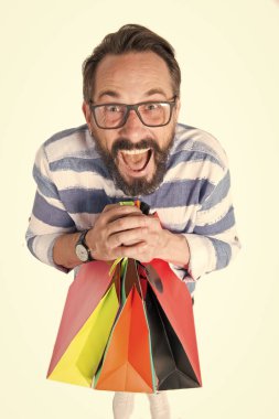 Adamın elinde bir sürü alışveriş torbası var. Alışveriş poşetleriyle şaşkın suratlı bir adam. Alışveriş konsepti. Kara Cuma 'da alışveriş yapan bir adam. Adam indirimli bir sürü şey almış..