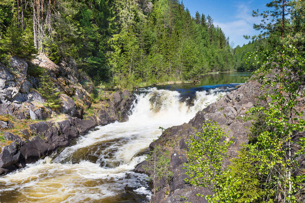 The Kivach waterfall on the background of forest and blue sky