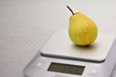Single Williams pear on a kitchen scale clipart
