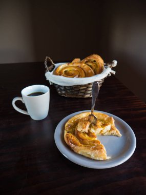 Fransız kuru üzüm hamur işleri ile beyaz bir levha ve hasır sepet üzerinde bir