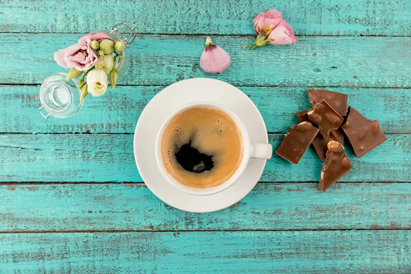 Taza de café vapor y flores en la mesa — Foto de Stock