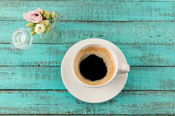 Koffie mok stoom en bloemen op tafel — Stockfoto