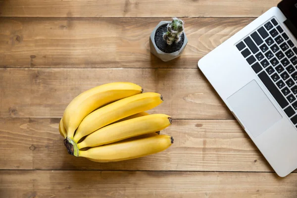 Ripe bananas and laptop — Stock Photo, Image