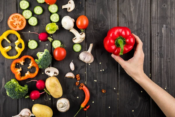 Fresh vegetables and hand with pepper — Stock Photo