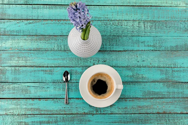 Taza de café vapor y flores en la mesa - foto de stock