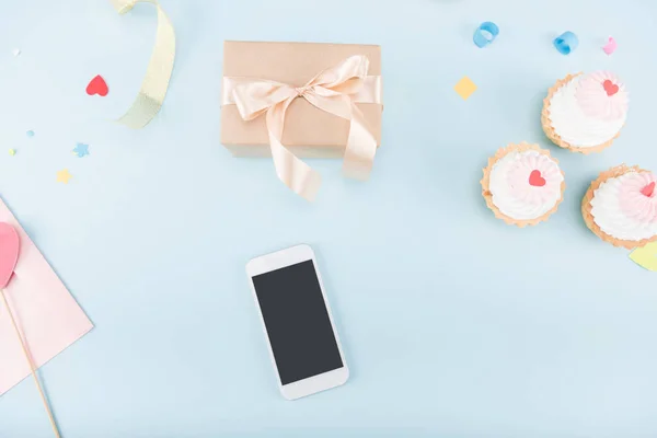 Cakes with smartphone and gift box — Stock Photo