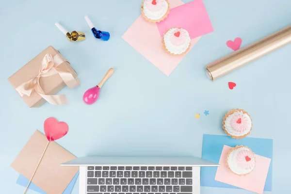 Cakes with laptop and party horns — Stock Photo