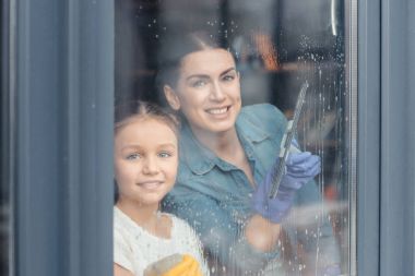 Mother and daughter cleaning window  clipart