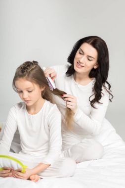 Mother combing hair of daughter  clipart