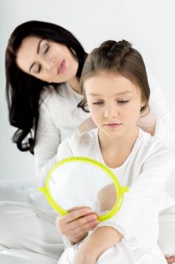 Mother combing hair of daughter  clipart