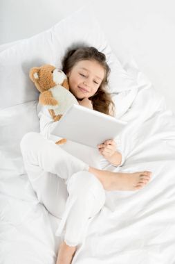 Kız yatakta dijital tablet ile 