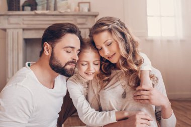 Mutlu genç aile ile bir çocuk oturma birlikte evde kucaklayan