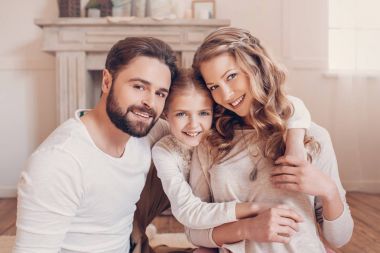 Mutlu genç aile sarılma ve kameraya gülümseyen bir çocuk ile 