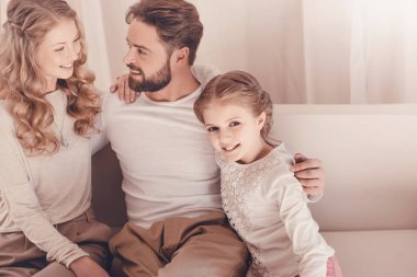 Mutlu genç aile ile bir çocuk oturma birlikte evde kucaklayan 