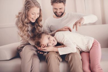 little happy daughter lying on parents lap and looking at camera clipart