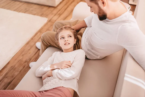 Urocza dziewczynka z szczęśliwy ojciec razem na kanapie w domu — Zdjęcie stockowe