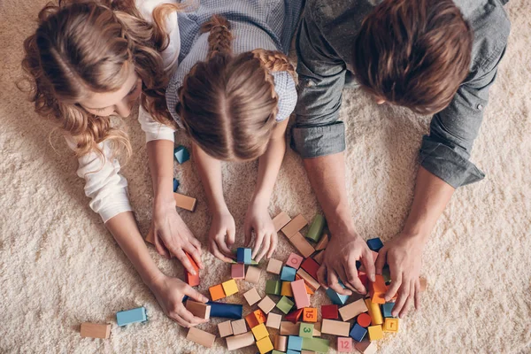 Familia feliz jugando con el constructor y acostado en el suelo en casa — Foto de Stock