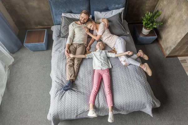 Feliz adorável filha com mãe e pai relaxante na cama em casa — Fotografia de Stock