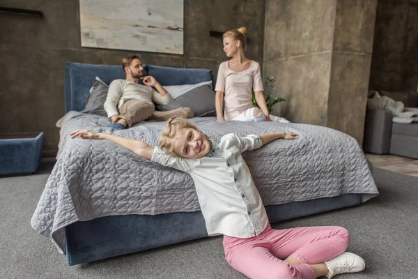 Feliz adorable hija con madre y padre relajándose en la cama en casa —  Fotos de Stock