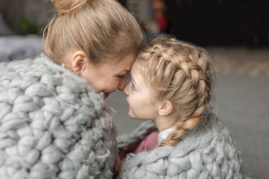 Güzel mutlu anne ve kızı birlikte Merinos yün battaniye altında oturan