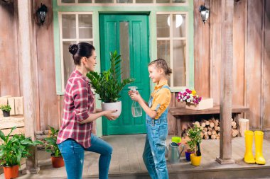 Anne ve kızı ile püskürtülen ilaç şişe, verandada duran bitki sulama