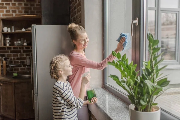 Janela de limpeza feliz mãe e filha com pano e frasco de spray juntos — Fotografia de Stock