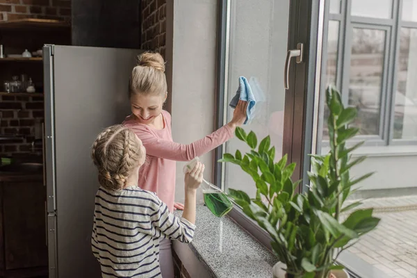 Feliz madre e hija limpiando la ventana y mirándose — Foto de Stock