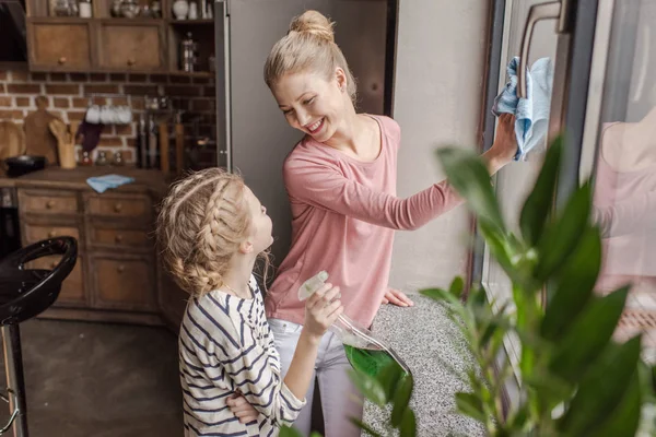 Mère et fille heureuses nettoient la fenêtre et se regardent — Photo