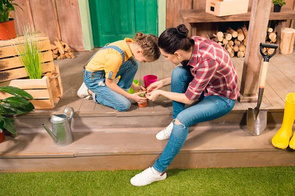 Mãe e filha felizes sentados juntos no alpendre e cultivando plantas — Fotografia de Stock