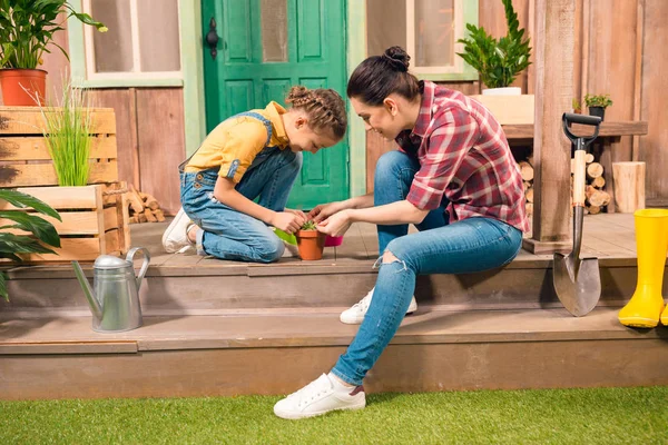 Happy mother and daughter sitting together on porch and cultivating plant — Stock Photo, Image