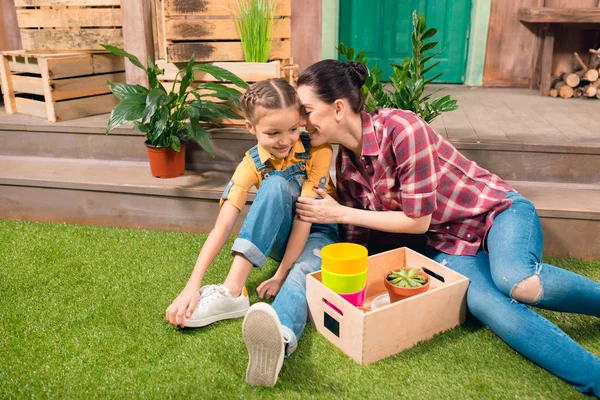 Lycklig mor och dotter sitter tillsammans på grön gräsmatta och pratar — Stockfoto