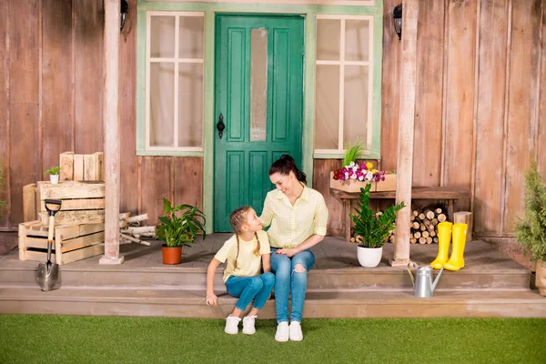 happy mother and daughter sitting on porch and looking at each other