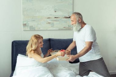 Olgun çift yatakta kahvaltı ile 