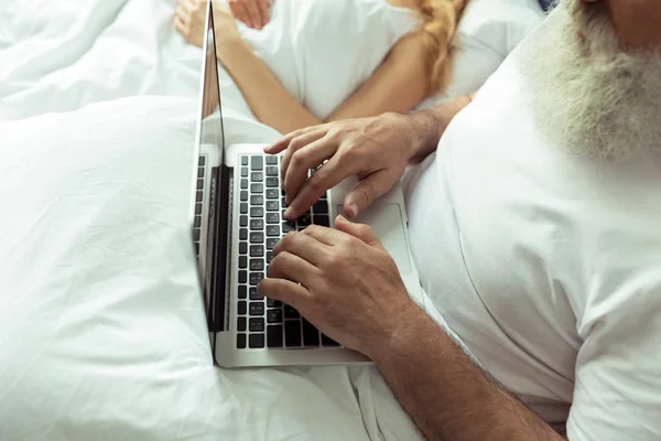 Mature couple in bed with laptop — Free Stock Photo