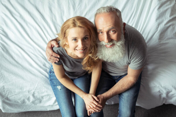 middle aged couple sitting on bed