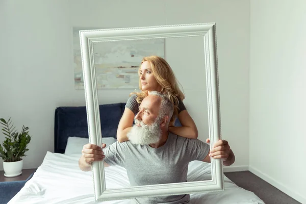 Middle aged couple with white frame — Stock Photo, Image