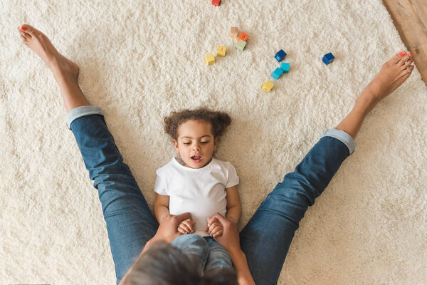 kid girl playing with mother on carpet