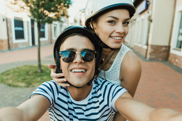 young couple in helmets taking selfie