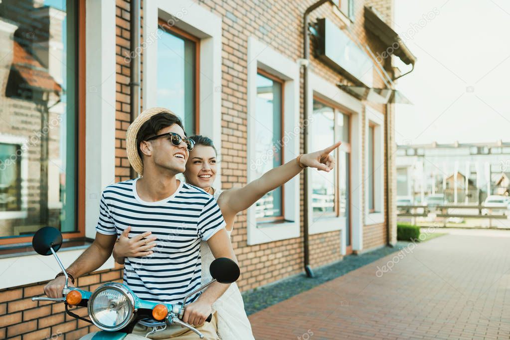 young smiling couple riding on moped