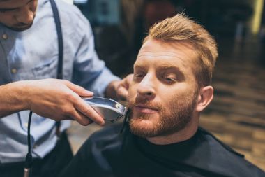 barber trimming customers beard