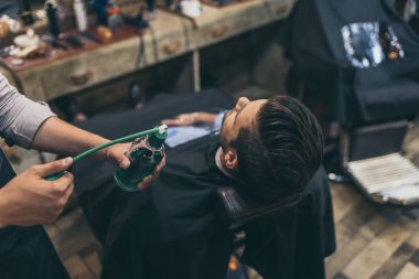 barber applying perfumes to customer clipart