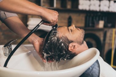 Kuaför müşterilerin saçını yıkıyor. 